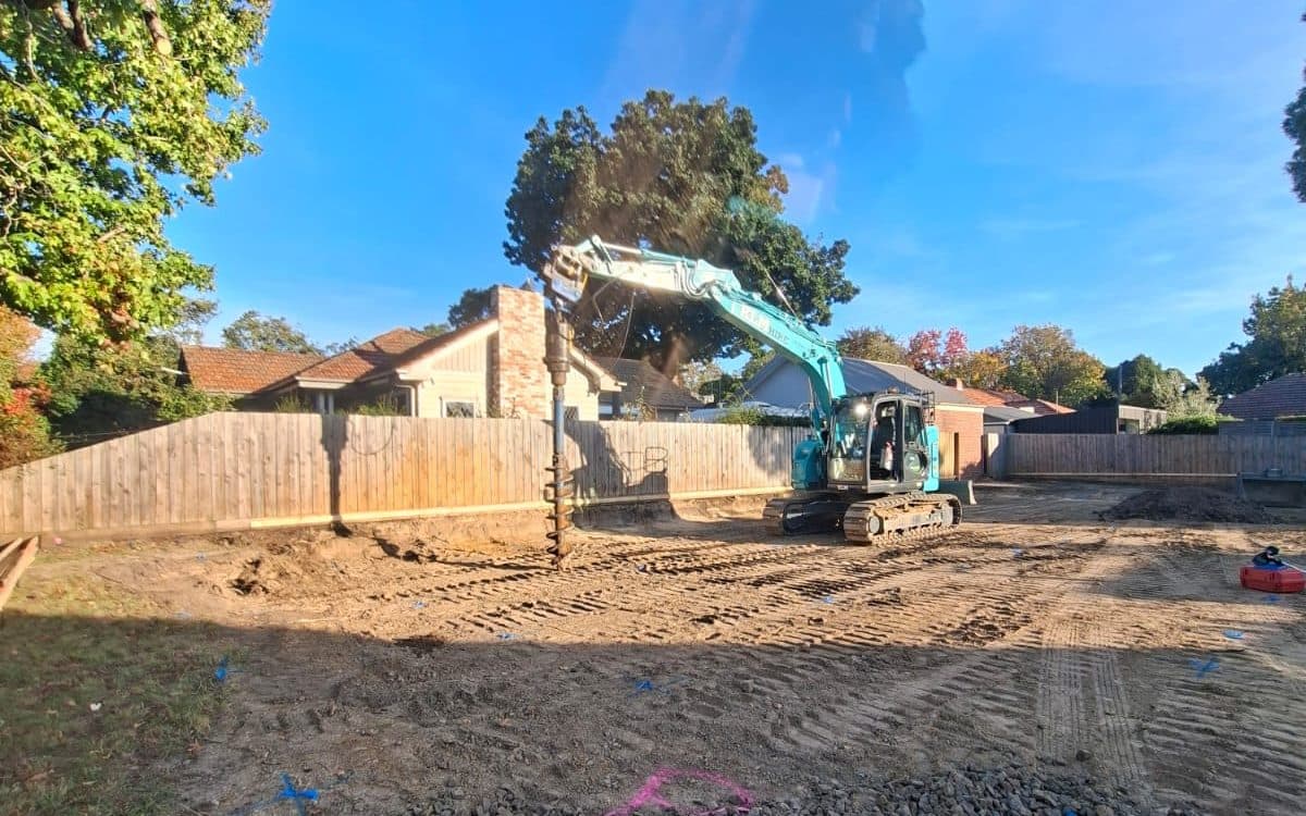 auger drilling fence post holes along a boundary line