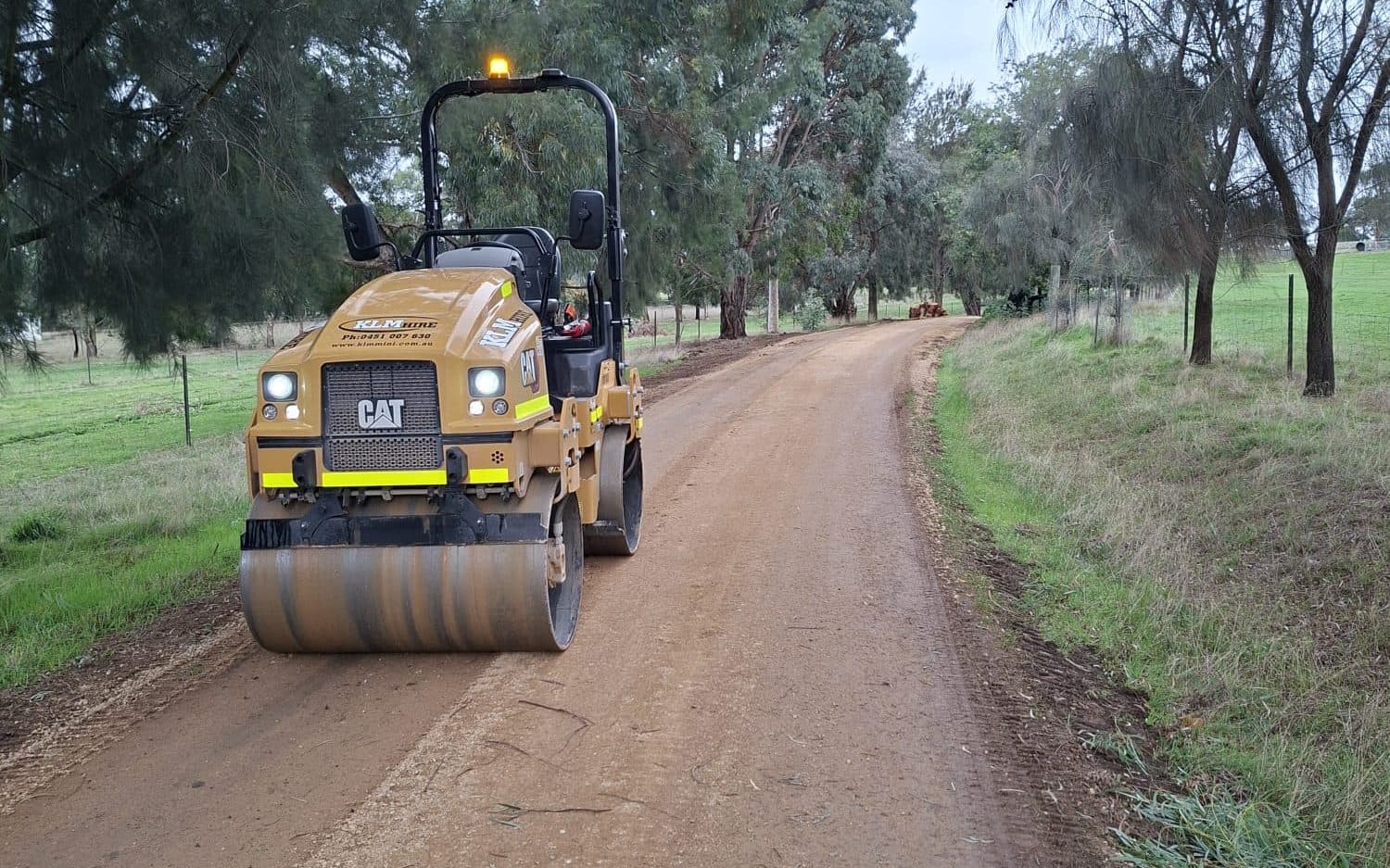roller compacting a crushed rock driveway between trees on a rural block