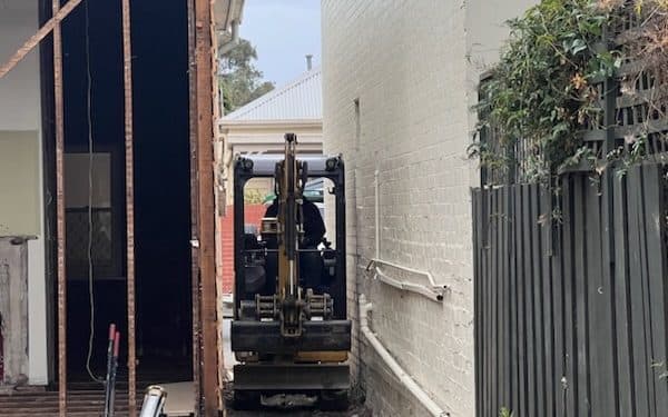 mini excavator working in the narrow gap between two houses