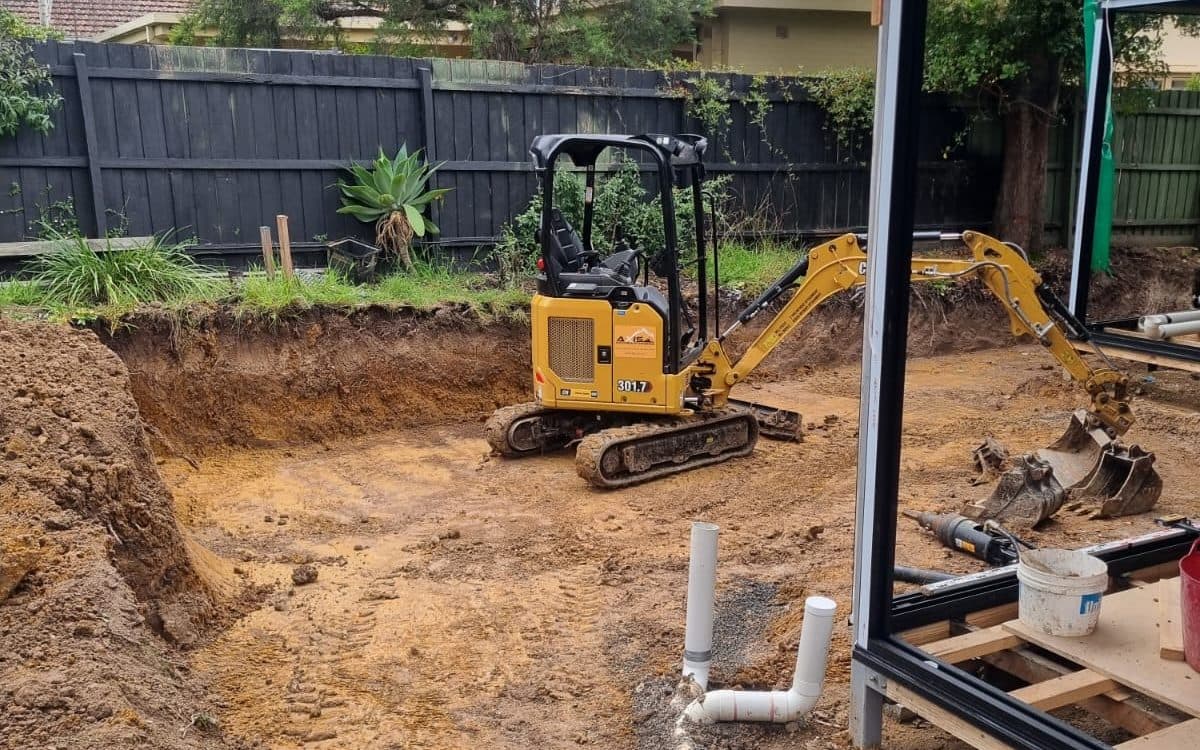 mini excavator and auger in an excavated backyard