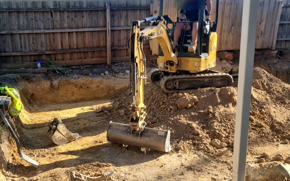 mini excavator digging out a rear yard behind a house