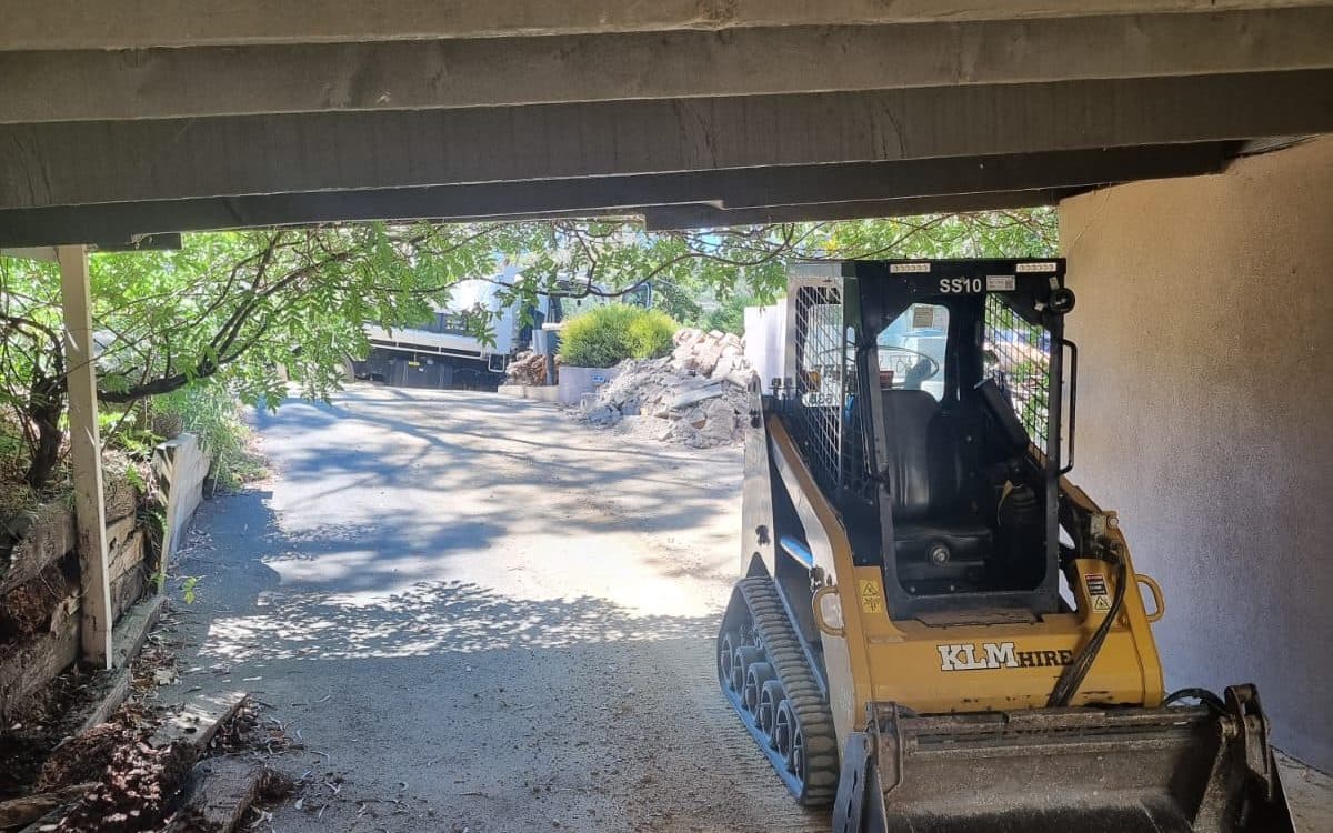 skid steer loader working under a low building overhang